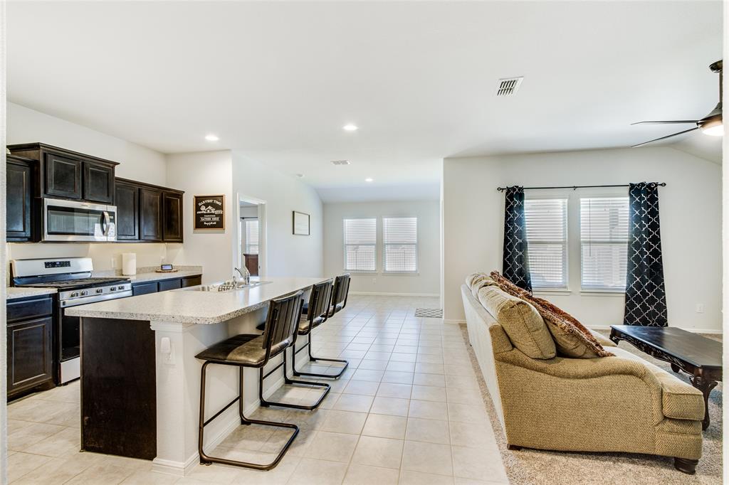 16516 Portage Street Justin, TX 76247 - Photo 7 of 29 a large white kitchen with stainless steel appliances granite countertop a sink a stove and a refrigerator
