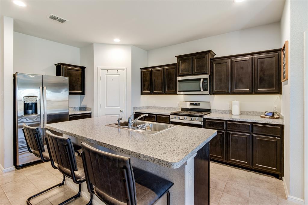 16516 Portage Street Justin, TX 76247 - Photo 8 of 29 a kitchen with stainless steel appliances a stove a sink island and a refrigerator