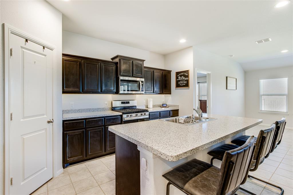 16516 Portage Street Justin, TX 76247 - Photo 10 of 29 a kitchen with stainless steel appliances a stove sink microwave refrigerator and cabinets