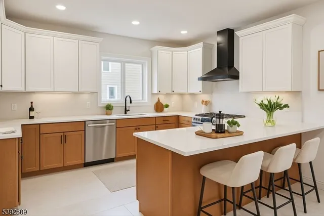 a kitchen with stainless steel appliances a sink a stove a refrigerator island and chairs
