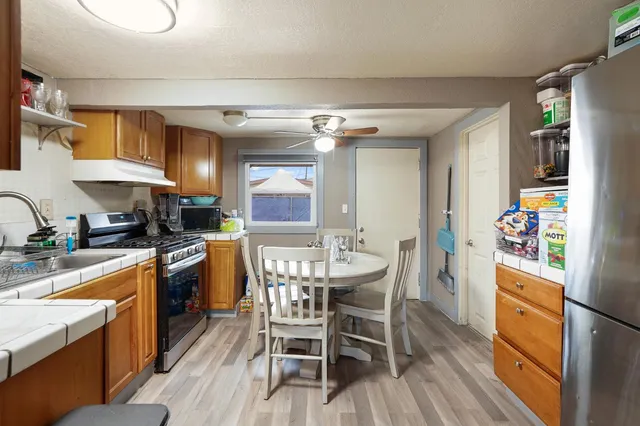a kitchen with granite countertop a dining table chairs sink and stainless steel appliances