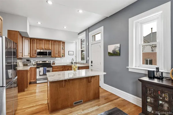 a kitchen with stainless steel appliances granite countertop a refrigerator a stove top oven a sink dishwasher and wooden cabinets with wooden floor