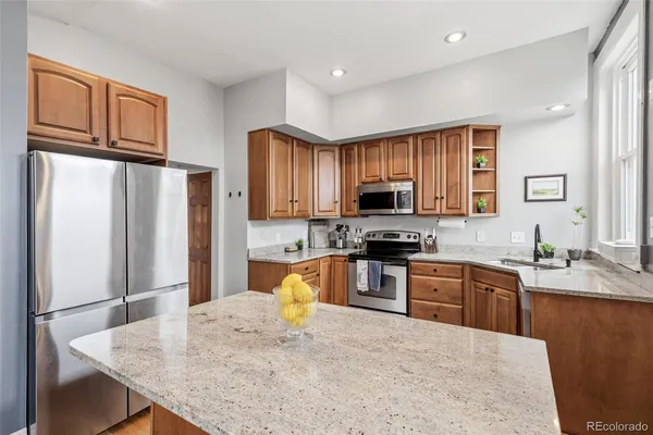 a kitchen with stainless steel appliances granite countertop a refrigerator and a stove top oven