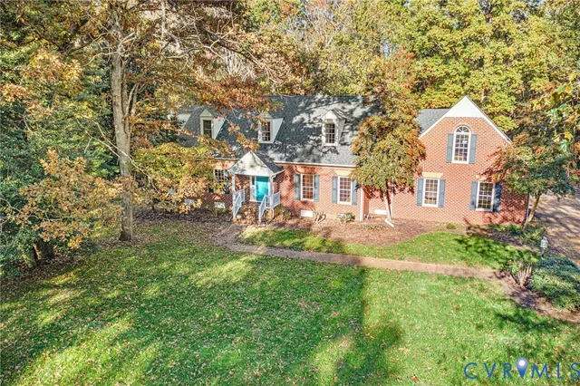 a view of white house with a big yard and large trees