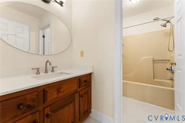 a bathroom with a sink vanity granite tub and a mirror