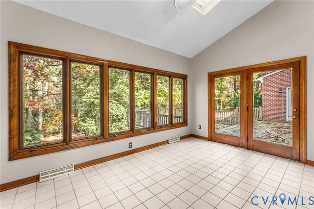 a view of an empty room with window and chandelier