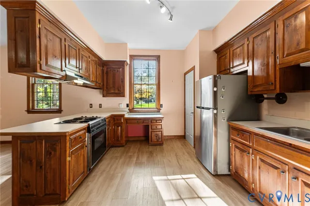 a kitchen with stainless steel appliances granite countertop a refrigerator a stove a sink and dishwasher a oven with wooden cabinets