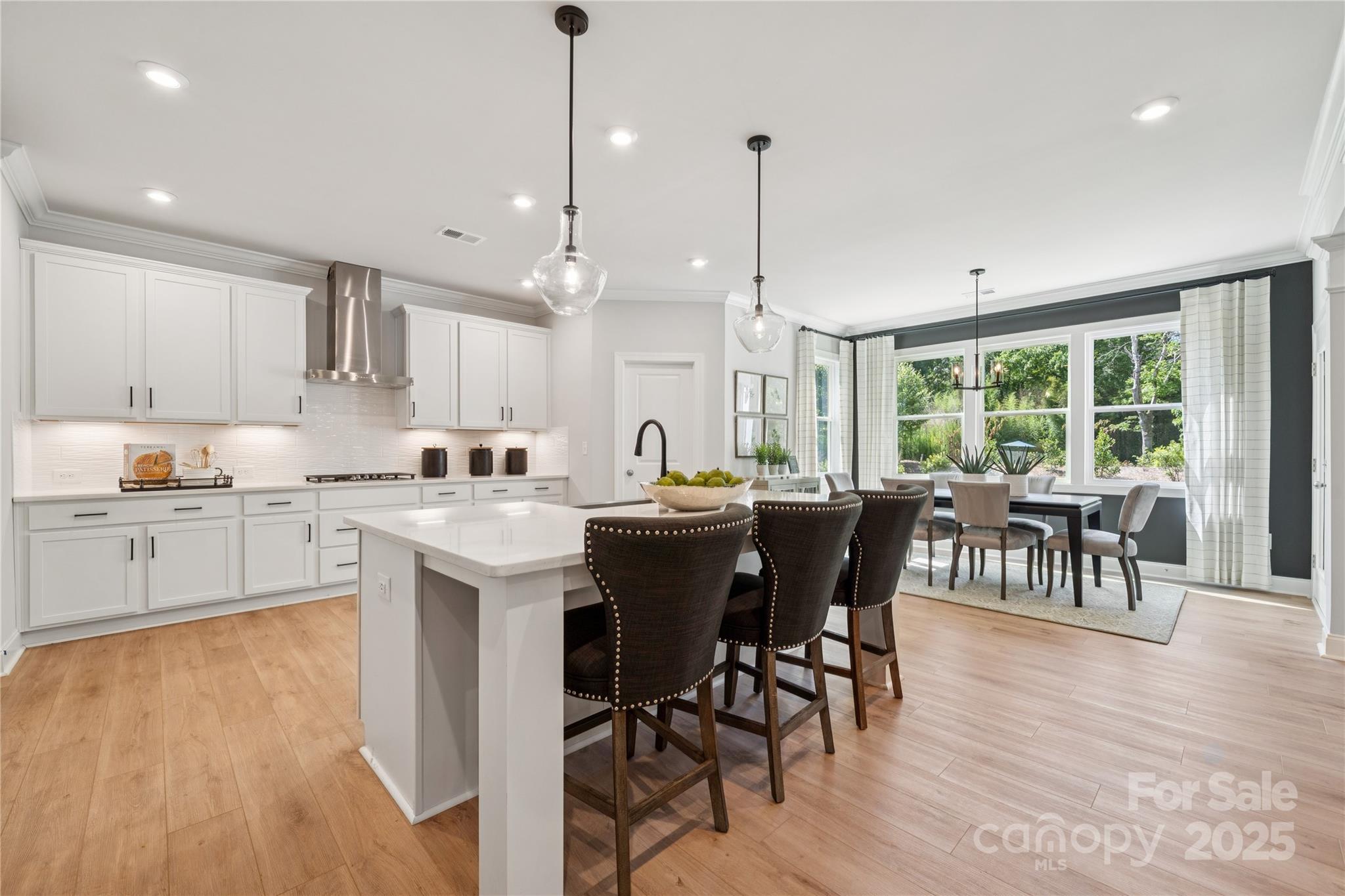 136 Balboa Street Matthews, NC 28104 - Photo 12 of 47 a kitchen with stainless steel appliances granite countertop a stove a refrigerator a kitchen island a dining table and chairs with wooden floor