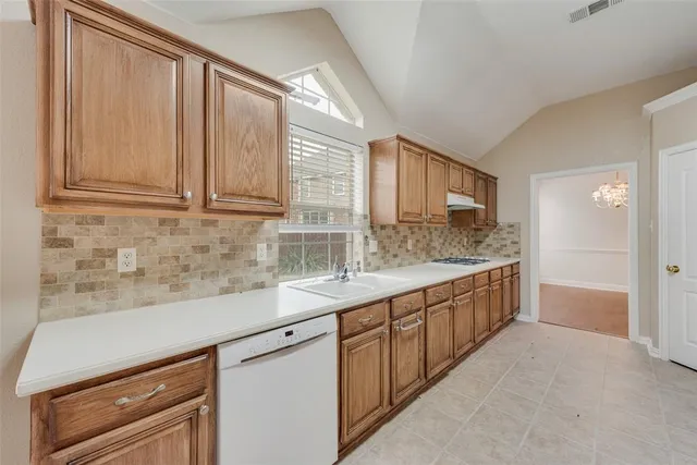a kitchen with granite countertop a sink stainless steel appliances white cabinets and a window