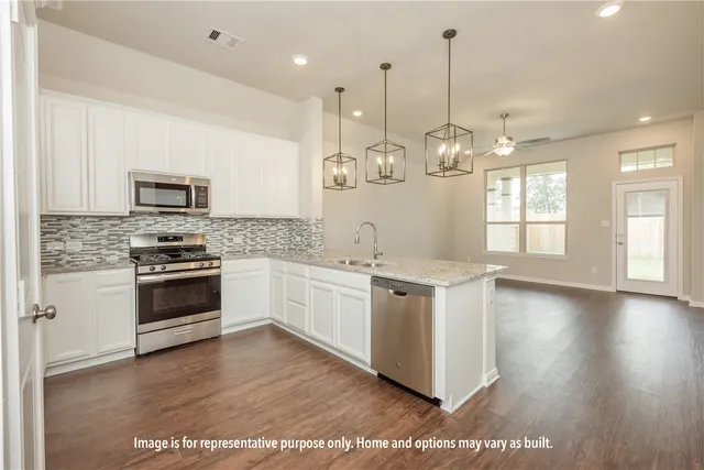 a kitchen with granite countertop a stove a sink dishwasher a refrigerator and a wooden floor