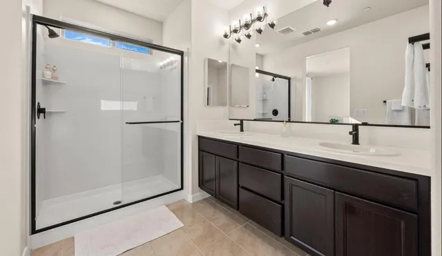 a bathroom with a double vanity sink mirror and shower