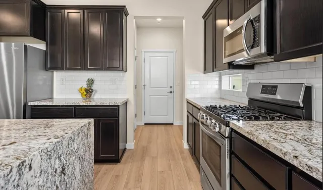 a kitchen with stainless steel appliances granite countertop a stove refrigerator and a microwave