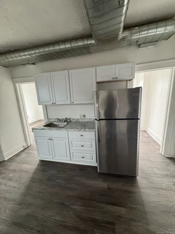 a view of a refrigerator in kitchen and an empty room