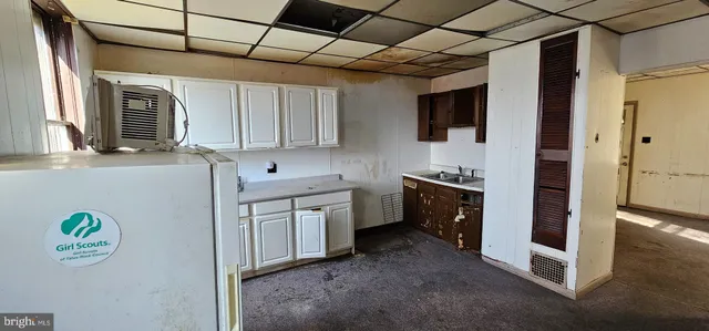 a view of a refrigerator in kitchen and a window in an empty room