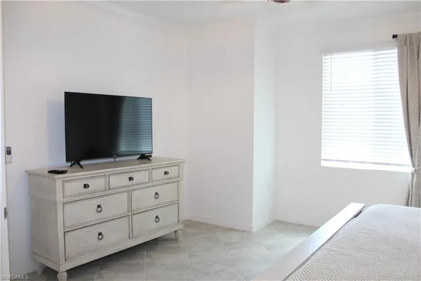 a living room with flat screen tv on dresser and a window