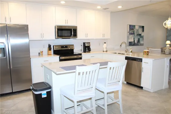 a kitchen with a sink a microwave a refrigerator and cabinets