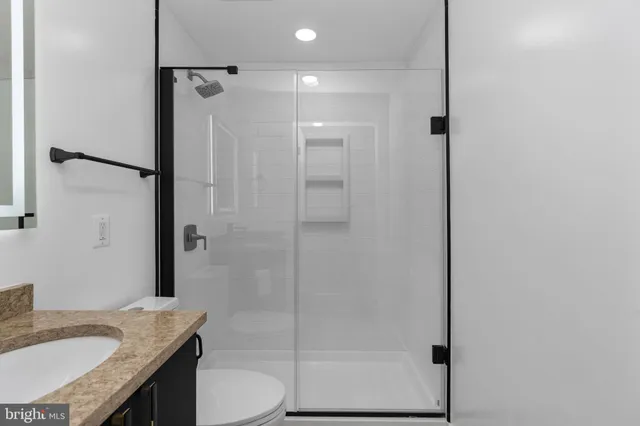 a bathroom with a granite countertop sink toilet and shower