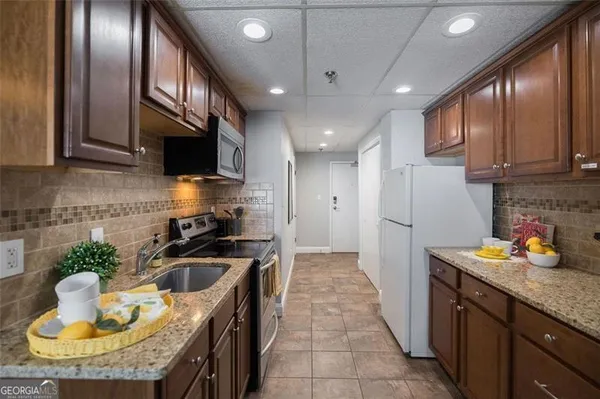 a kitchen with granite countertop kitchen island stainless steel appliances a sink a stove and a refrigerator