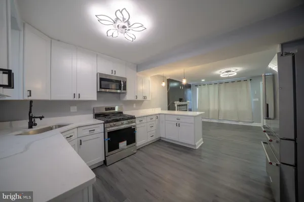 a large kitchen with a stove a sink dishwasher a refrigerator and a oven with wooden floor