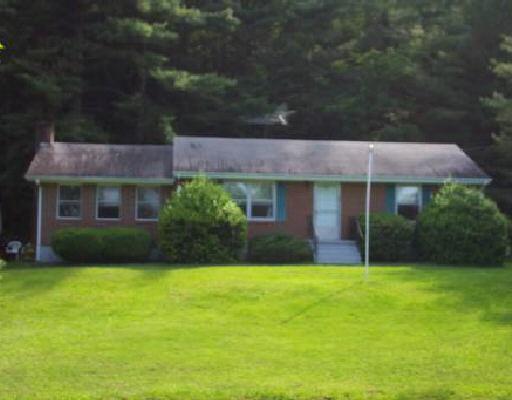 a view of a brick house with a yard and large trees