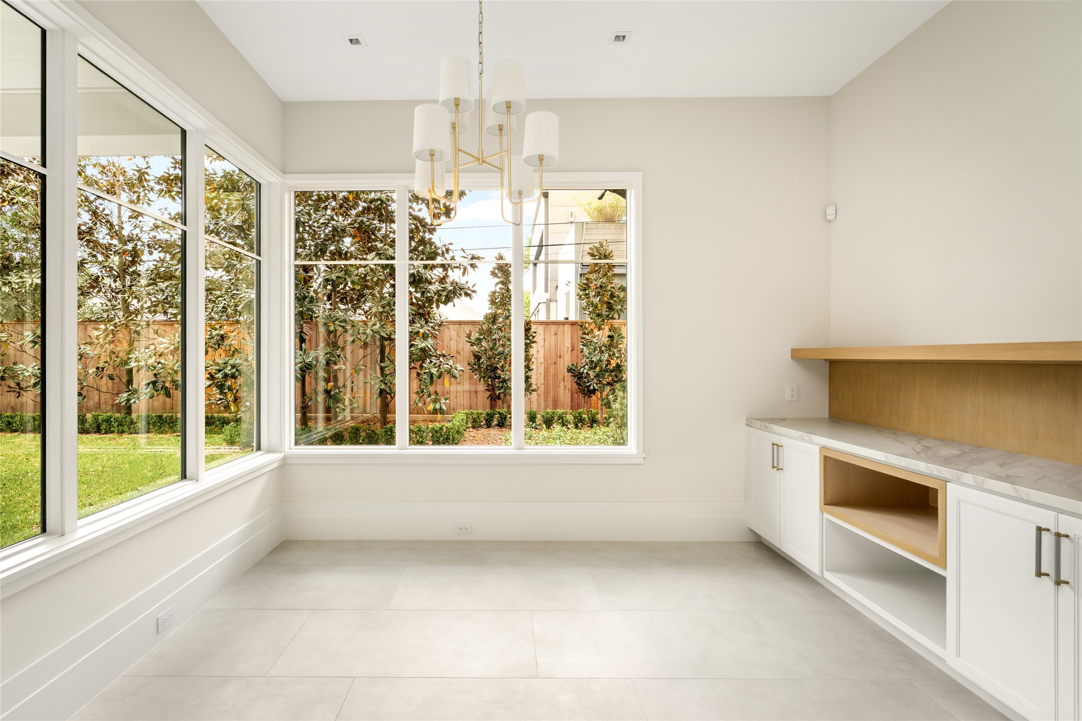 4006 Overbrook Lane Houston, TX 77027 - Photo 15 of 50 Sunlit breakfast room framed by expansive windows, featuring built-in storage with white oak rift accents and subtle under-cabinet lighting.