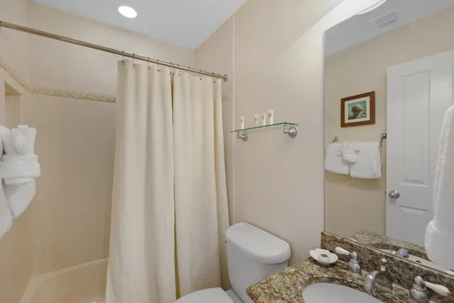 a bathroom with a granite countertop toilet and a shower