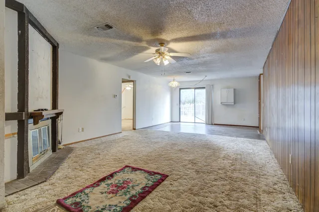 an empty room with a chandelier fan and closet