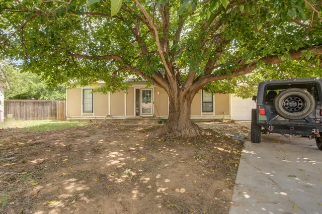 a view of a house with a tree next to a yard