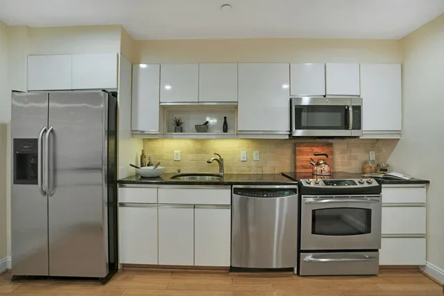 a kitchen with granite countertop white cabinets and stainless steel appliances