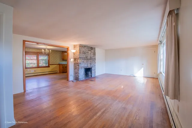 a view of empty room with wooden floor and fireplace