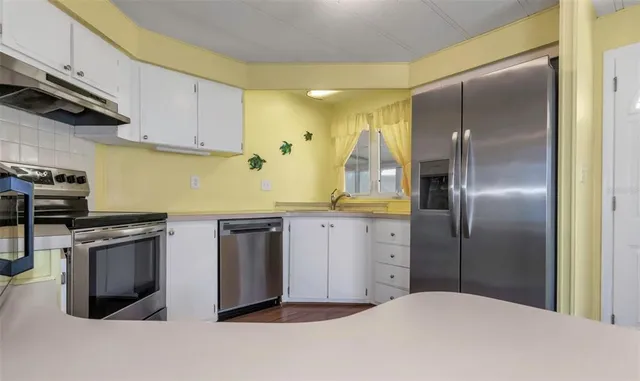 a kitchen with stainless steel appliances granite countertop a refrigerator a sink a stove and white cabinets