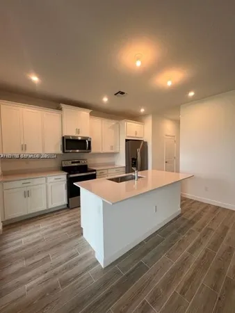 a kitchen with stainless steel appliances kitchen island granite countertop a stove a sink and a refrigerator