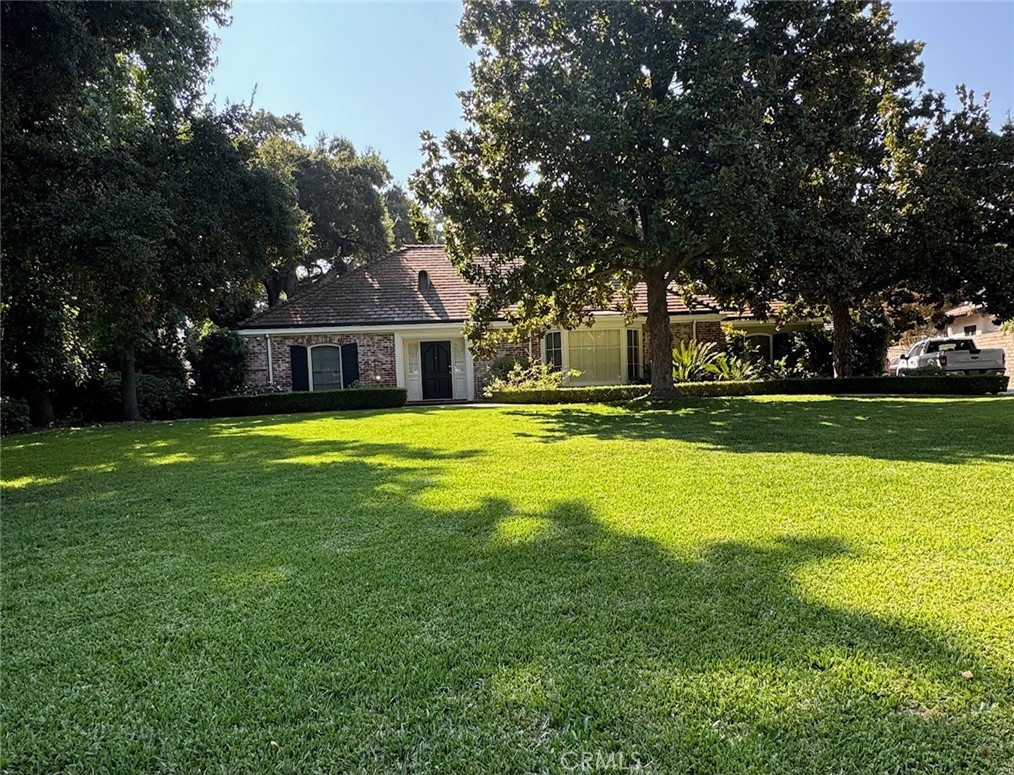 a view of a house with a big yard and large trees