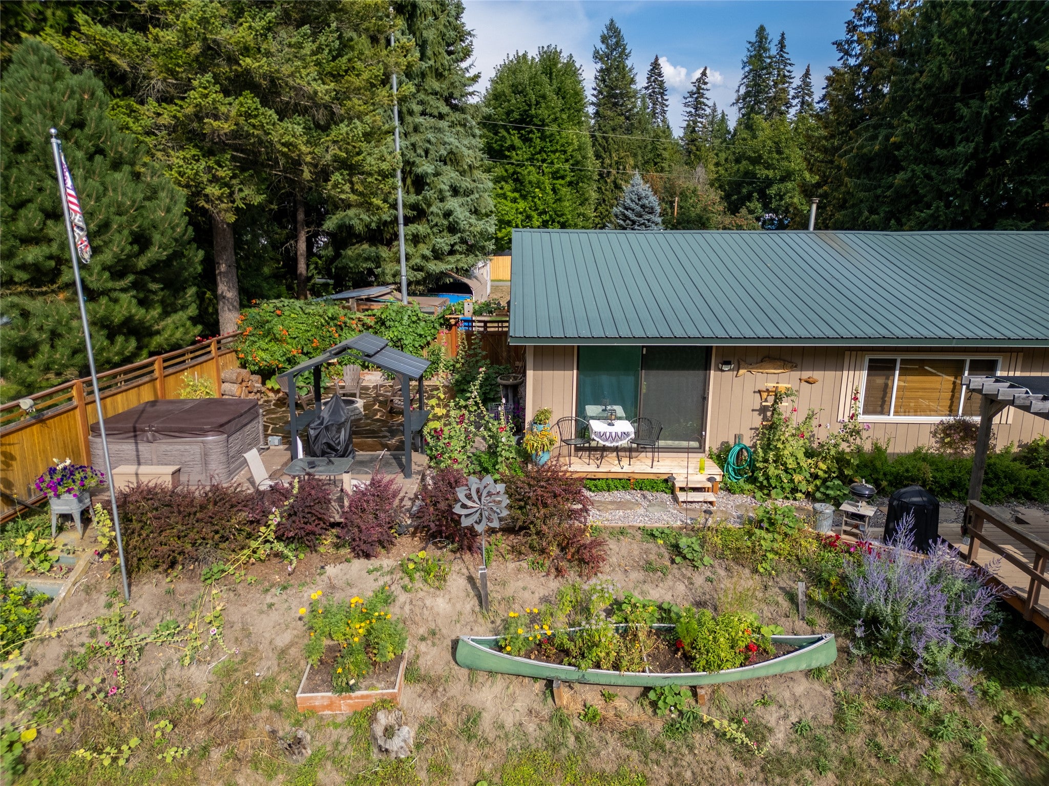 644 Waterfront Road Troy, MT 59935 - Photo 12 of 66 Rear view of house with a metal roof, a jacuzzi, a patio area, a wooden deck, and a fenced backyard