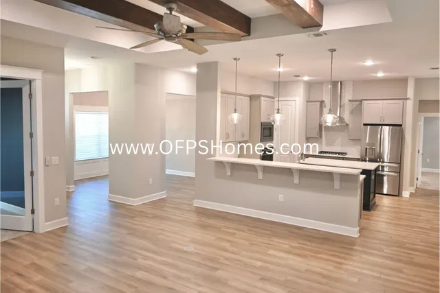 a view of kitchen with stainless steel appliances kitchen island granite countertop a refrigerator a stove and a wooden floors