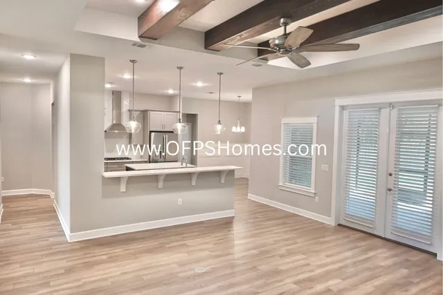 a view of a kitchen with kitchen island a refrigerator wooden floor and a window