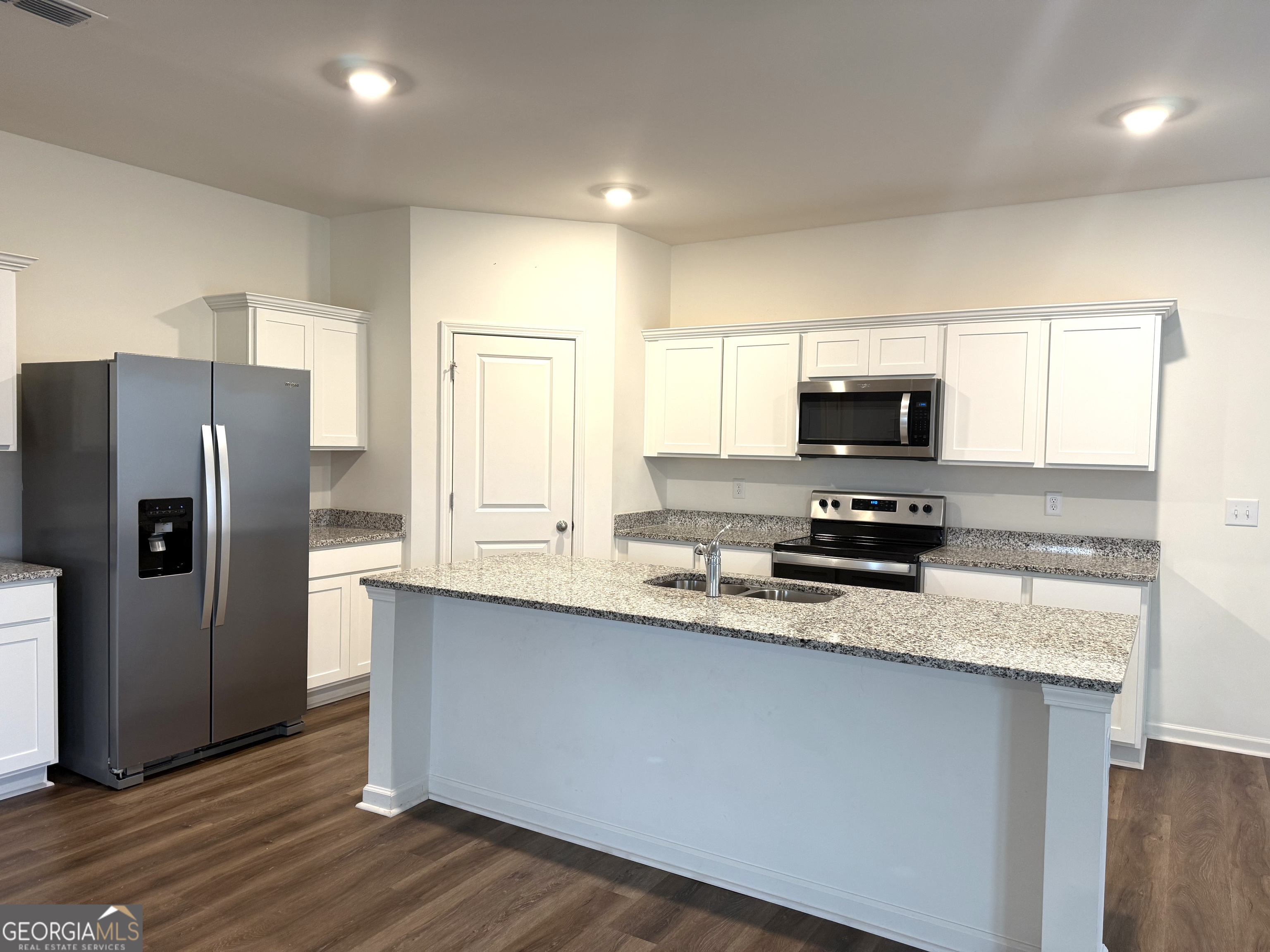 119 Pond Court Hoschton, GA 30548 - Photo 4 of 29 a kitchen with kitchen island granite countertop a refrigerator a sink a stove a microwave and wooden floor