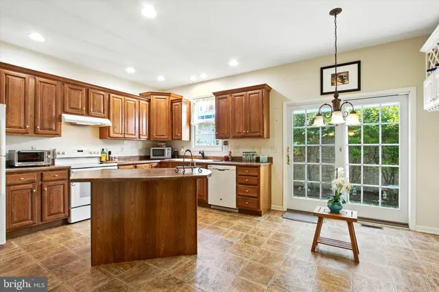 a kitchen with kitchen island granite countertop a stove a sink a counter top space and cabinets