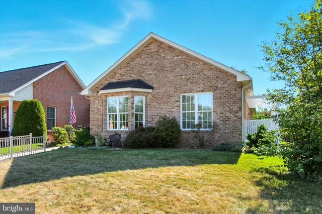a view of a house with brick walls plants and large tree
