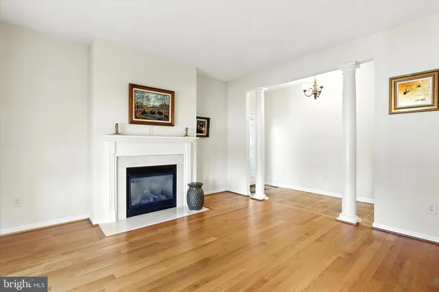 a view of a livingroom with a fireplace a ceiling fan and wooden floor