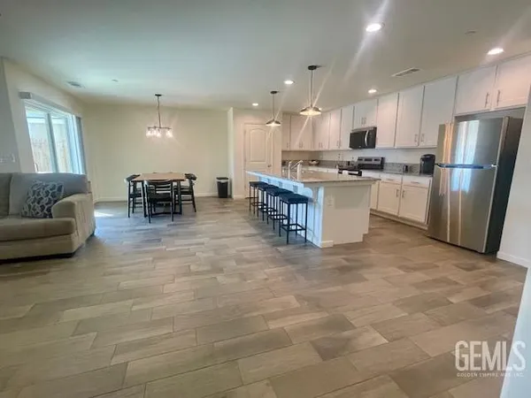 a kitchen with stainless steel appliances kitchen island granite countertop a refrigerator a stove a sink and a dining table