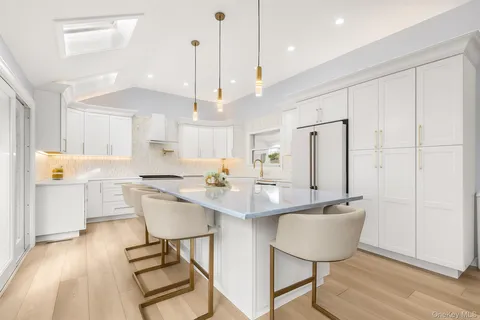 a kitchen with stainless steel appliances granite countertop a sink a stove a refrigerator and island with wooden floor