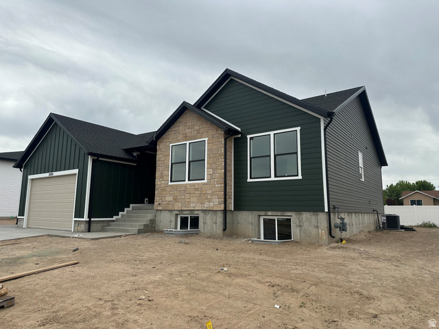 3839 West 825 North, Unit WF18 West Point, UT 84015 - Photo 3 of 22 Contemporary exterior featuring dark green siding, stone accents, black-trimmed windows, a light-colored garage door, and a concrete pathway