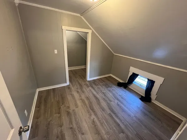 a view of an empty room with wooden floor and stairs