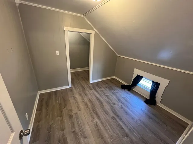 a view of an empty room with wooden floor and stairs