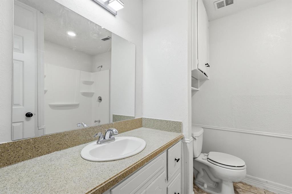 756 East Pecan Street Hurst, TX 76053 - Photo 4 of 19 a bathroom with a granite countertop sink toilet and a mirror