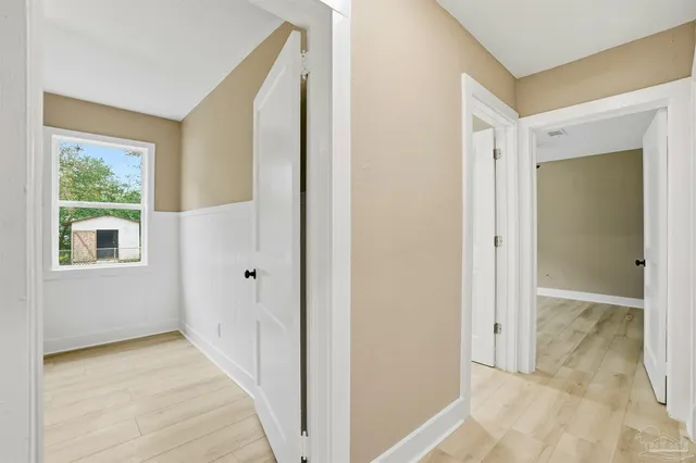 a view of a hallway with wooden floor and a bathroom