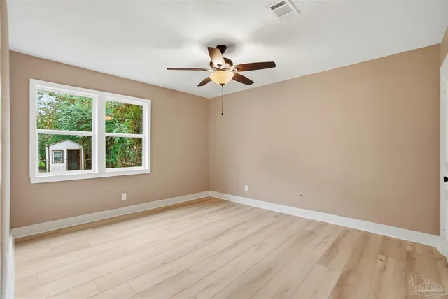 an empty room with a window and a fan
