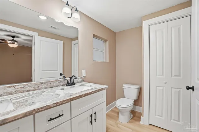 a bathroom with a granite countertop toilet a sink and a mirror