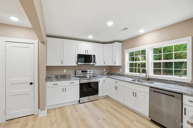 a kitchen with stainless steel appliances granite countertop a stove sink and cabinets